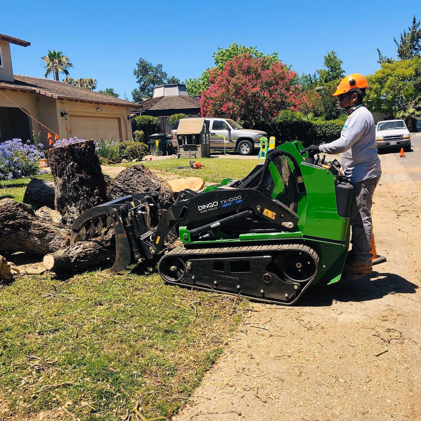 Environmental Tree Service: compact track loader pulling a stump from a front yard